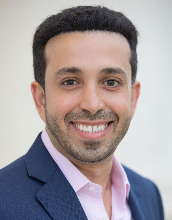 Man wearing a suit smiling at the camera.